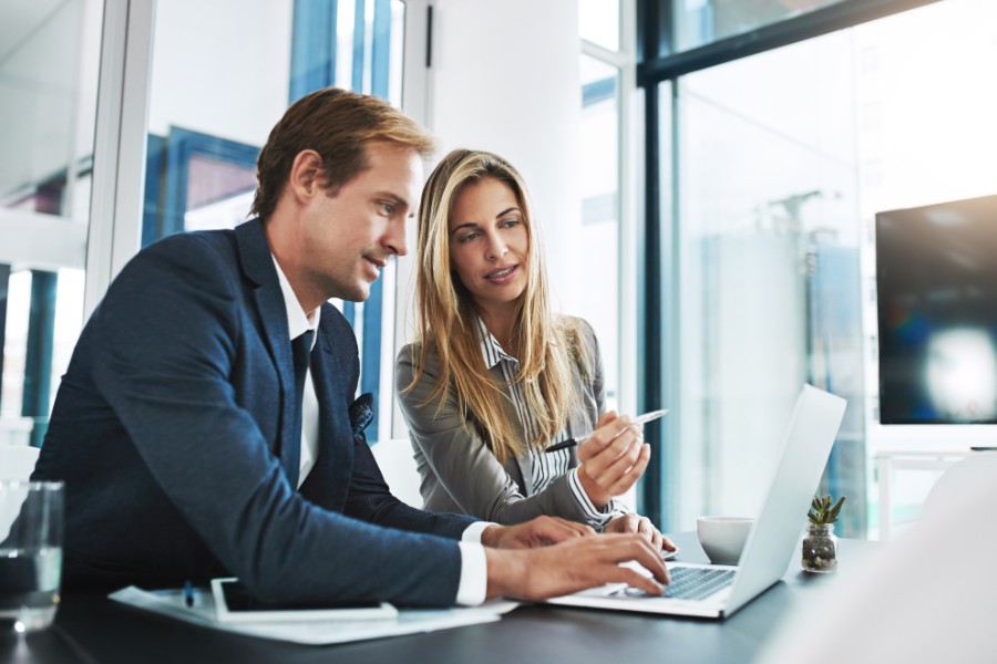 Man, woman and partnership with research, laptop and typing with help, explain and coaching in workplace. Businessman, female partner and computer for business goal, teamwork or training at job